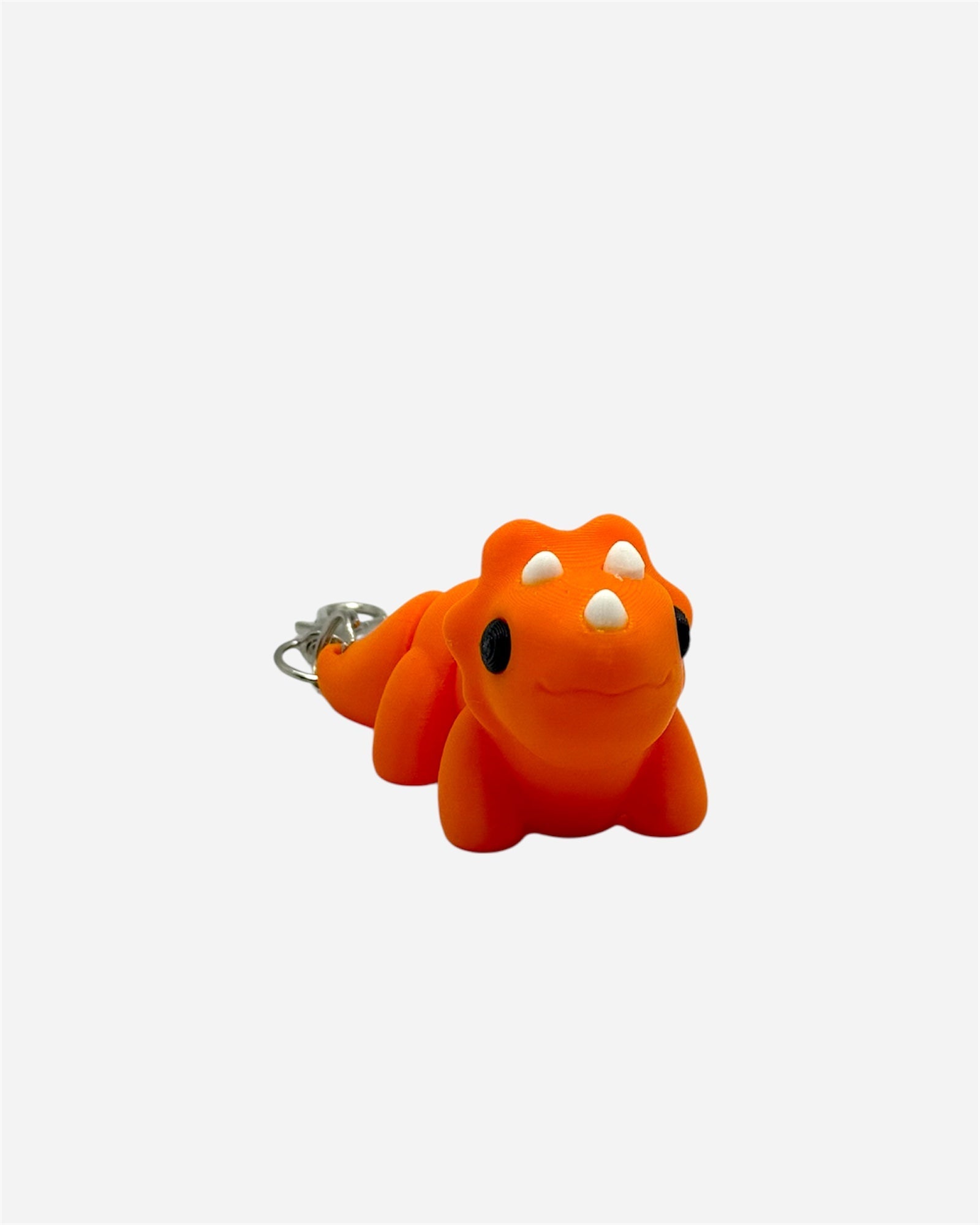 Orange dinosaur-shaped keychain on a white background